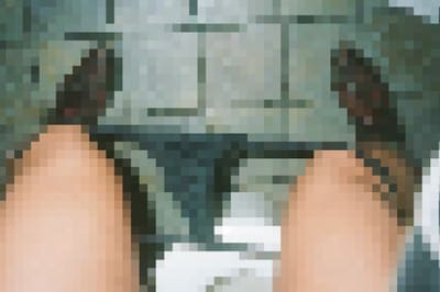 Pixelated top-down view of two bare knees with a dark garment between them over a tiled floor