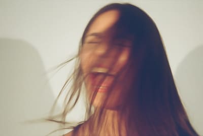 Motion-blurred photo of a laughing person with long hair swinging across the face